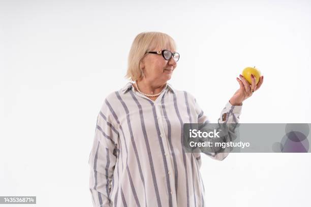 Senior Woman Holding An Apple Against White Background Stock Photo - Download Image Now