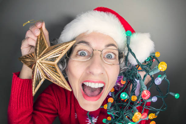 A humorous fisheye image of a super excited Christmas crazy woman in a Santa hat holding lights and a star decoration.