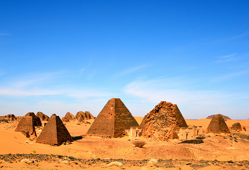Meroë, Begarawiyah, Kush, Sudan: Nubian pyramids of Meroe, tombs of the Kushite kingdoms - South Necropolis and North Necropolis (foreground and background respectively) - located 200 kilometers northeast of Khartoum near the village of Bagrawiya, spread over small hills. In total there are more than 900 pyramids and tombs. The pyramids, mostly built of stone, are significantly smaller than the Egyptian pyramids with a height of less than 30 meters and served as burial places for the kings, queens and high officials of the historical empire of Kush in Nubia. Construction ranges from around 300 BC to about AD 300. The first pyramid at Meroe that can be attributed to King Ergamenes, who died about 280 BC.