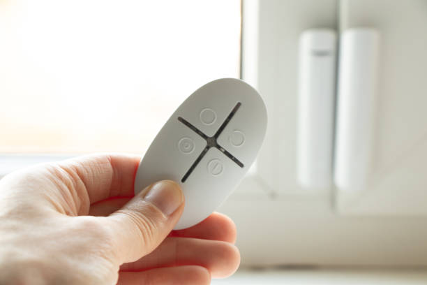 istock home security system on the windows, an opening sensor and a remote control in the hands of opening and closing, a remote control from the house alarm 1435375571