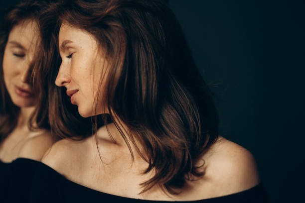 Elegant woman in a white shirt poses in front of white background