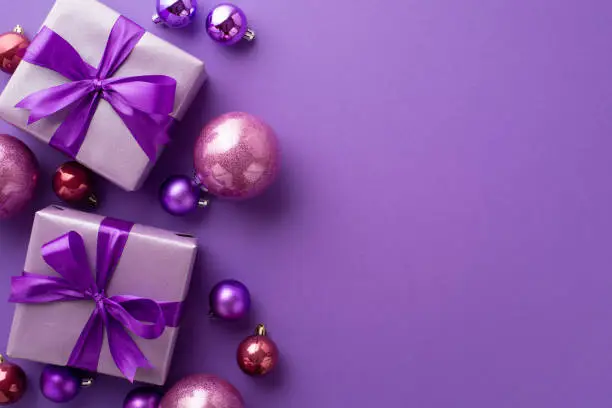 Photo of Christmas Day concept. Top view photo of lilac gift boxes with ribbon bows pink and purple baubles on isolated violet background with copyspace