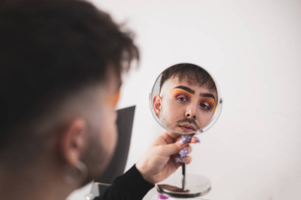 istock a gay boy looks through a mirror as he puts on makeup.modern man concept. 1435383672