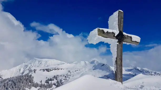 Snow and ice covered summit cross in the Austrian Alps. Laterns, Vorarlberg, Austria.
