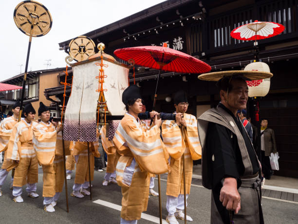 Local men in traditional costumes carrying a portable shrine along the narrow streets of Takayama old town during the annual Takayama Autumn Festival parade stock photo