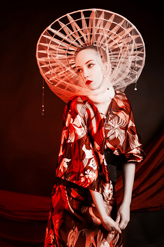 Geisha in kimono. Asian woman in hat with red lips on black background. Beauty makeup. Asian fashion.