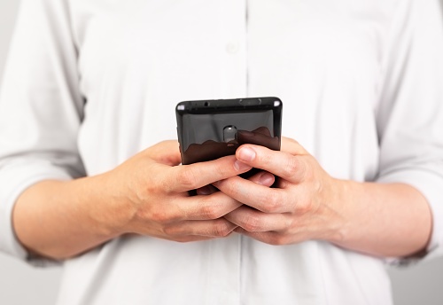 Woman hands texting message at phone. Female using Android for instant messaging, sharing photos, videos in messengers or typing SMS. Frontal view. High quality photo