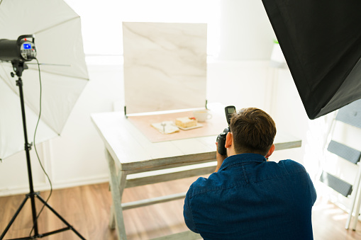 Rear view of a photographer at his studio using his camera with a softbox and professional lighting equipment