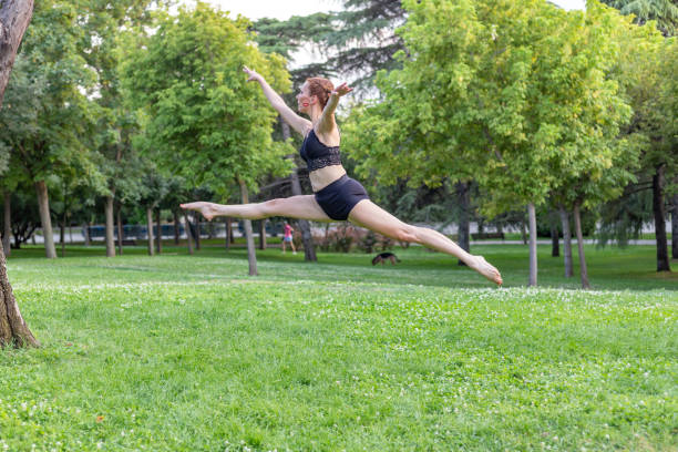 istock White female dancer jumping in public park on grass 1435395503