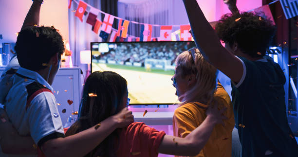 group of young happy asian people watch football match on television at home, cheer celebrate goal score together at night. doha qatar world cup 2022, sport fan supporter, or friends party concept - world cup 個照片及圖片檔