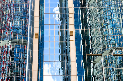 Closeup glass wall of office building with reflection of office buildings, background with copy space, full frame horizontal composition