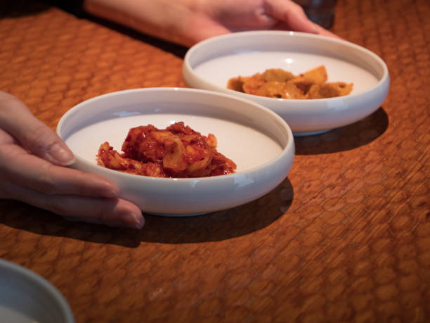 Hands picking at side dishes in a Korean restaurant.