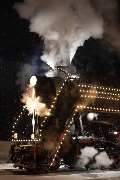 istock festively decorated with lights retro Christmas train on rails, snowy evening 1435399094