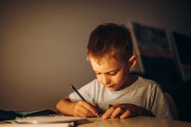 istock Child holding a pen and writing / drawing in low light 1435399185