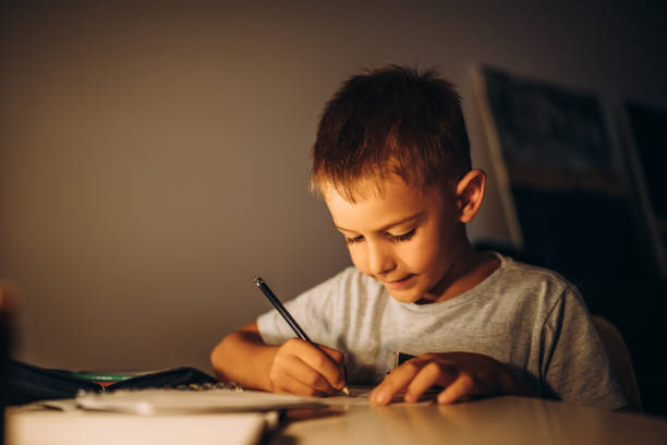 istock Child holding a pen and writing / drawing in low light 1435399219