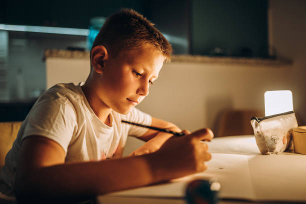 Child holding a pen and writing / drawing in low light
