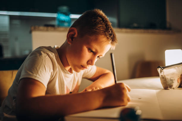 istock Child holding a pen and writing / drawing in low light 1435399274