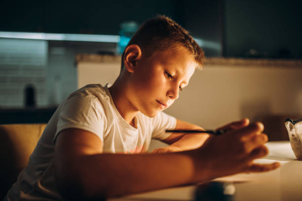 istock Child holding a pen and writing / drawing in low light 1435399729