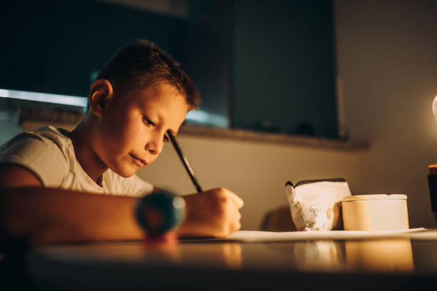 istock Child holding a pen and writing / drawing in low light 1435399744