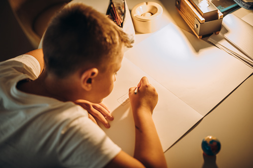 Child holding a pen and writing / drawing in low light