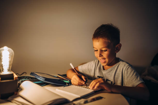 istock Child holding a pen and writing / drawing in low light 1435400008