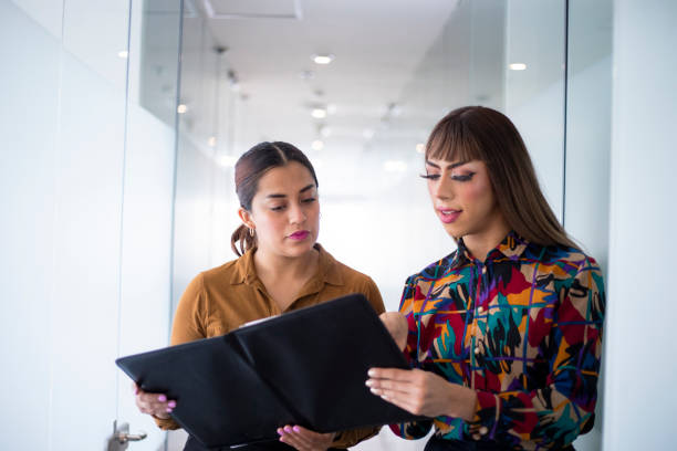 young woman and trans woman in the office young woman and trans woman in the office transgender stock pictures, royalty-free photos & images