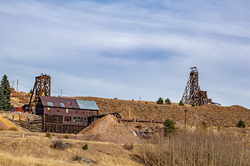 Scenic view of old rusted equipment on blooming landscape near abandoned wooden building at Bodie State Historic Park.