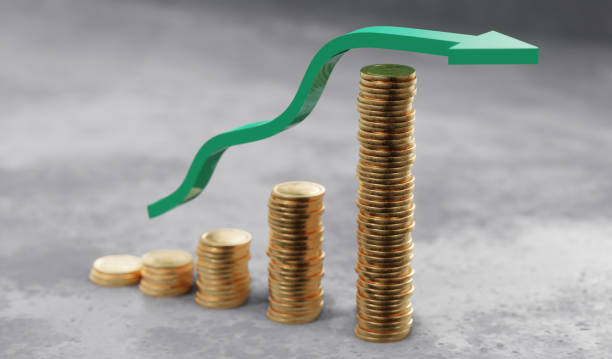 Graph of a green profit arrow rising upwards over coins. Growing investment concept. stock photo