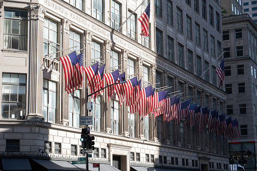New York, NY, USA - June 4, 2022: American flags on the facade of the Saks Fifth Avenue flagship store on Fifth Avenue in Midtown Manhattan.