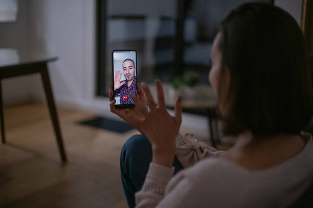 Woman at home talking to her boyfriend on a video call Woman at home talking to her boyfriend on a video call using her cell phone - lifestyle concepts long distance relationship stock pictures, royalty-free photos & images