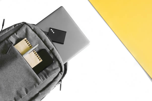 istock Gray urban backpack with a laptop, notepad, pen, external ssd and smartphone on white and yellow background. Lifestyle concept with gadgets. Backpack concept for the modern student. 1435449336