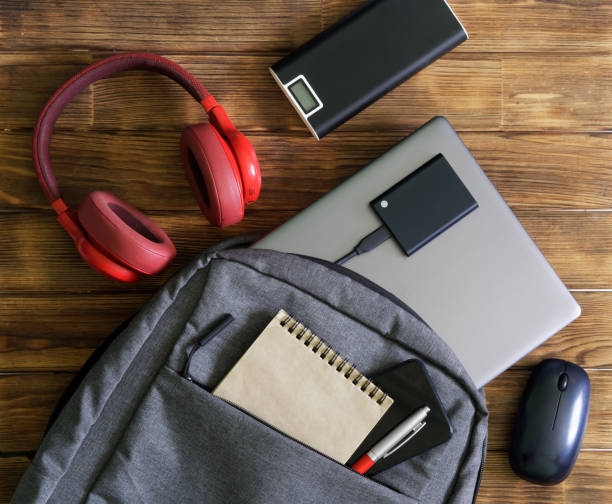 istock Modern gadgets and gray textile backpack or bag on wooden table. Laptop, portable ssd, smartphone, notepad, pen, headphones, mouse and external battery - poverbank. For work and study. 1435449348