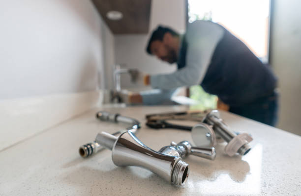 Plumber fixing a leak in the kitchen sink of a house stock photo