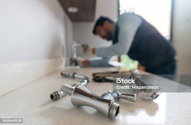 Plumber Fixing A Leak In The Kitchen Sink Of A House Stock Photo - Download Image Now