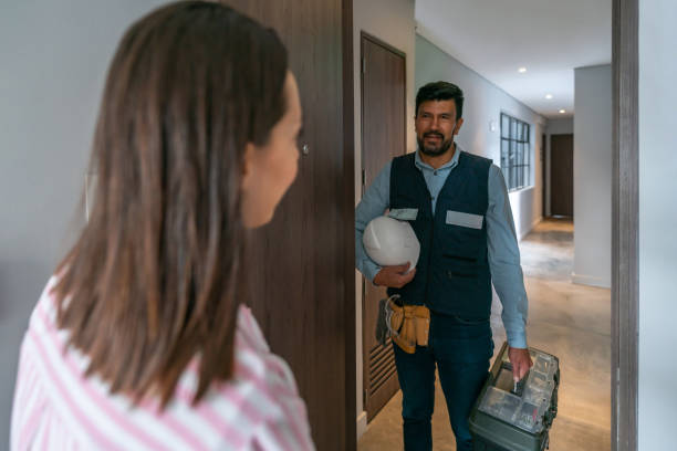 Woman at home opening the door to a repairman Woman at home opening the door to a repairman coming to fix a problem in her house door repairman men manual worker stock pictures, royalty-free photos & images