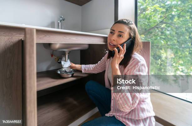 Woman Having A Leak In Her Kitchen Sink And Calling The Plumber Stock Photo - Download Image Now