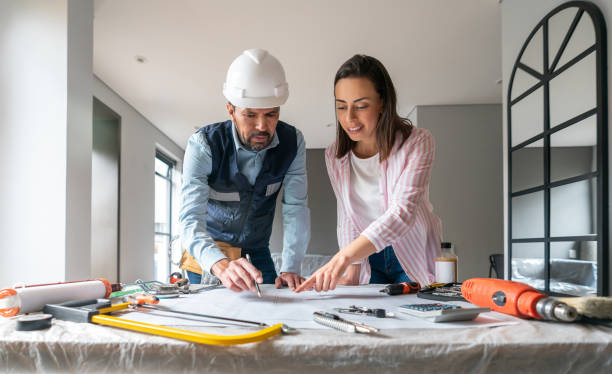 istock Woman and contractor looking at some blueprints while renovating her house 1435449568