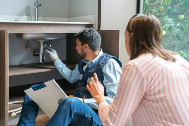 Photo of Plumber explaining to a client the problem with her kitchen sink