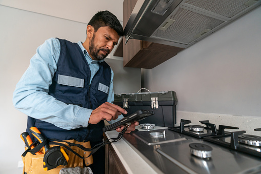 Supervisor making a gas inspection at a house and checking for leaks in the stove using a meter device