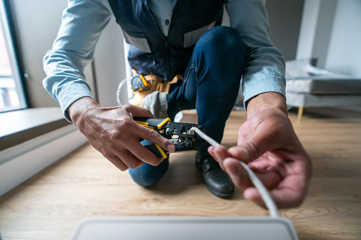 Internet technician installing a router at a house and cutting the cable