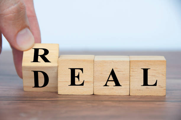 istock Hand turning wooden cube to form real deal text. 1435455526