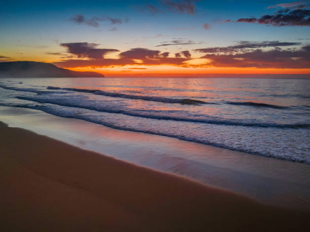 istock Orange dawn breaks over the ocean with small waves and clouds 1435460917