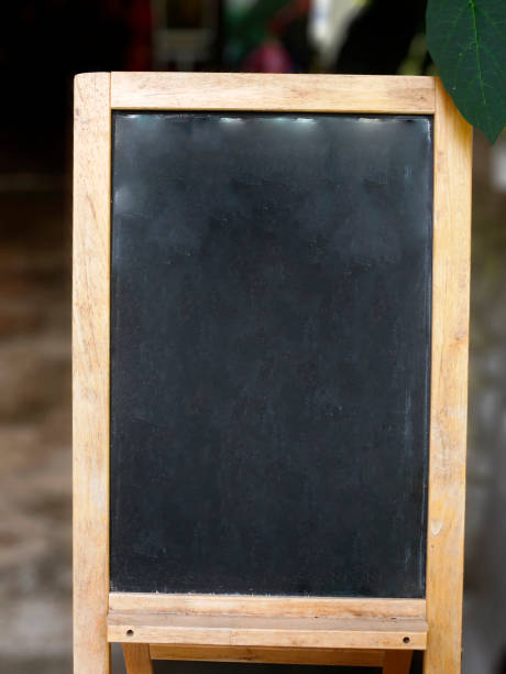 istock Empty black board, chalk board, wooden frame stand sign with a green leaf and blurred background 1435462432