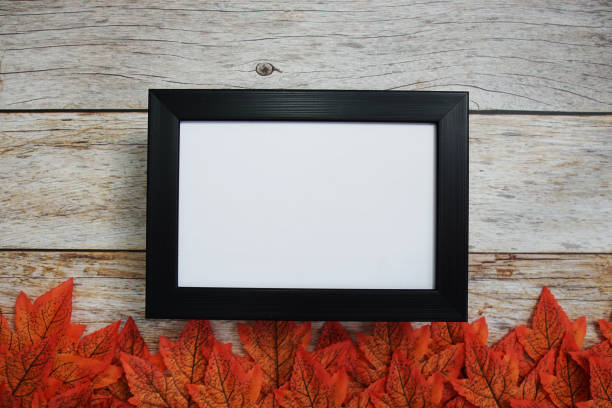 istock Empty mock up photo frame with maple leaves on wooden background 1435469229