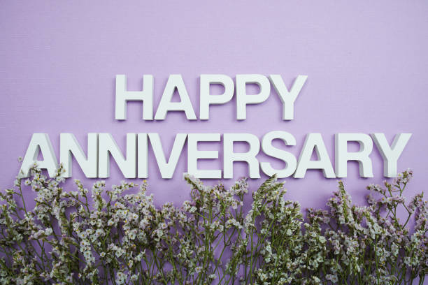 istock Happy Anniversary alphabet letters with flower frame on purple background 1435471749