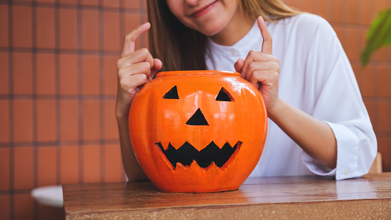 Closeup image of a young woman playing with a Halloween pumpkin bowl for Halloween festival concept