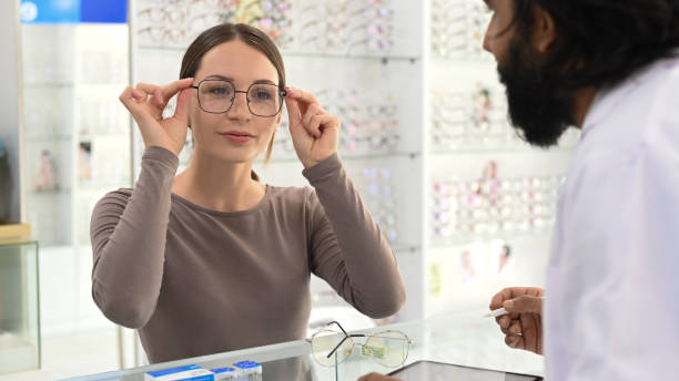istock Smiling young woman testing new glasses with optometrist at optical store. Eyesight and vision concept. 1435490728