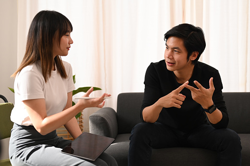 Happy young couple enjoying conversation, spending time together at cozy home.