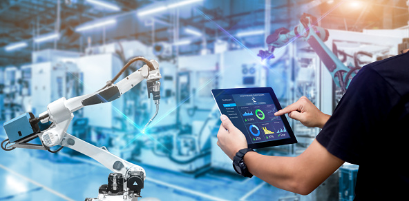 Engineer Hands holding tablet on blurred robot arm automation machine as background