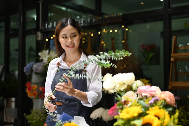 istock Attractive female florist cutting branches, creating beautiful bouquet with with different flowers. 1435491119